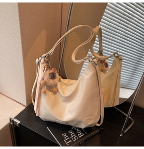 Dettaglio borsa a tracolla bianco crema in pelle PU lucida con ciondolo alpaca
