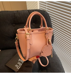 Pink bucket bag with lychee grain texture featuring a cute puppy charm and golden hardware