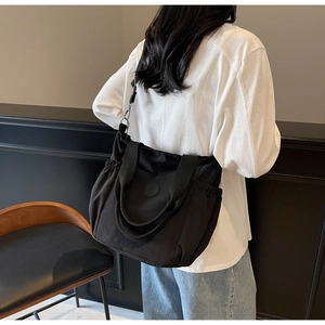 Detail of black canvas tote bag showing side drawstring pocket and adjustable strap