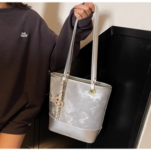 Dettaglio della borsa tote argento metallizzato con motivi a rilievo tenuta da modella