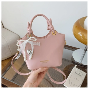 Rosa Lederbeutel Tasche mit Perlenanhänger und weißer Spitzenschleife im Detail