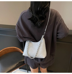 Detailansicht einer weißen gesteppten Schultertasche mit silberner Kette unter dem Arm