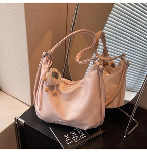 Dettaglio borsa a spalla rosa chiaro con ciondolo peluche e nastro decorativo a pois