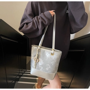 Dettaglio della borsa tote argento con trame in rilievo di farfalle e fiori eleganti