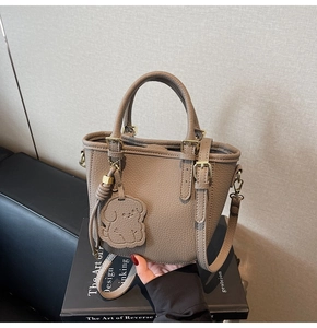 Detail of tan pebble leather tote with champagne gold hardware and puppy charm