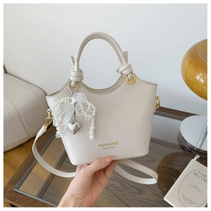 Detailansicht der cremefarbenen Ledertasche mit Perlenspitze und Herzanhänger