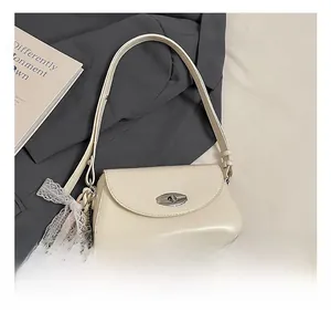 Gros plan du sac à bandoulière crème avec fermoir métallique et nœud en dentelle
