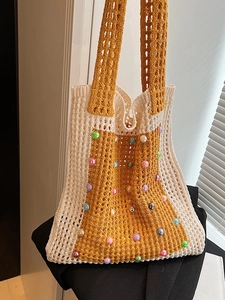 Knitted crochet tote bag with colorful beads and wide yellow shoulder strap on a jacket