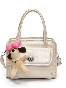 Cream pearl finish handbag with silver twist lock and cute puppy plush charm on white background