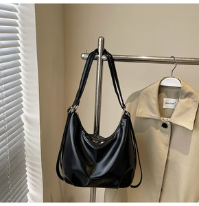 Dettaglio di una borsa tote in pelle PU nera lucida con logo ovale goffrato sul fondo