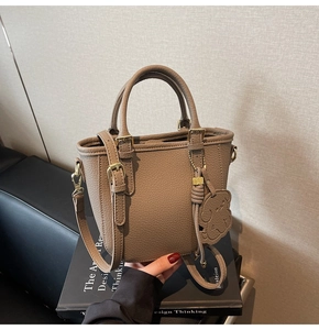 Close-up of litchi texture leather bucket bag with cute dog charm and gold hardware
