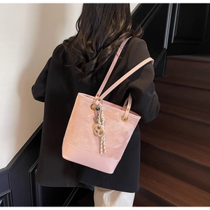 Dettaglio ravvicinato della borsa tote rosa goffrata con motivi floreali e ciondolo