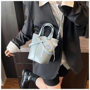 Détail du sac seau bleu clair avec design à sangles croisées et breloque en perles