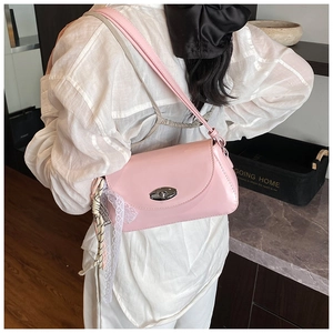 Détail du sac à bandoulière en cuir verni rose avec boucle argentée et dentelle sur modèle