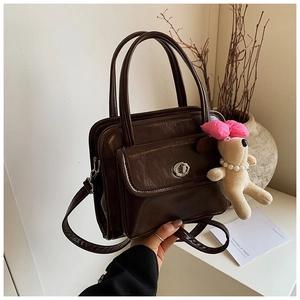 Detail of a dark brown PU leather bowling bag with silver twist lock and dog plush charm