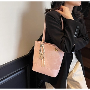 Dettaglio della borsa a spalla rosa chiaro con motivi a rilievo e ciondoli decorativi