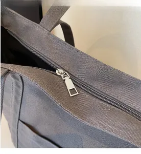 Close-up of smooth silver metal zipper and textile texture on grey canvas tote bag