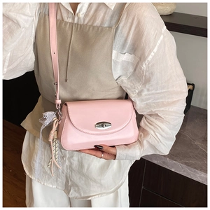 Détail du sac à bandoulière rose clair avec fermoir rotatif argenté et pompon en dentelle
