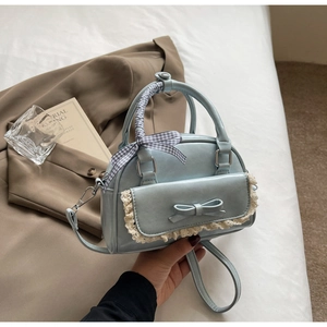 Detail van lichtblauwe crossbodytas met kant, strik en geruite zijden sjaalhandgreep