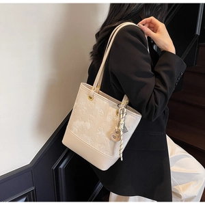 Dettaglio della borsa tote bianco crema con motivi a rilievo e decorazioni