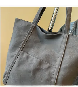 Detail of dark gray canvas tote bag featuring green embroidery and spacious outer pocket