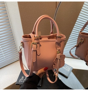 Detailed macro of pink lychee textured leather tote with golden hardware and bear charm