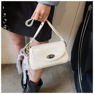 Détail du sac à bandoulière en similicuir crème avec fermoir argenté et ruban de dentelle