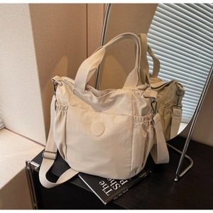 Detail of cream canvas tote bag showing side drawstring pockets and adjustable shoulder strap