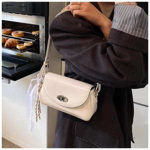 Détail du sac sous le bras crème avec boucle métallique et pendentif décoratif en dentelle