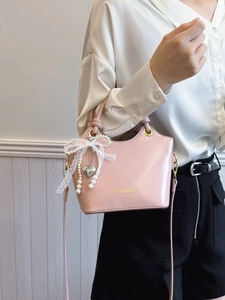 Rosa Handtasche aus Kunstleder mit Schleife und Perlenkette an einem Model