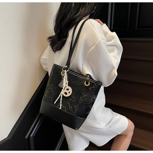 Dettaglio di una borsa tote nera goffrata con cuciture eleganti e un ciondolo decorativo