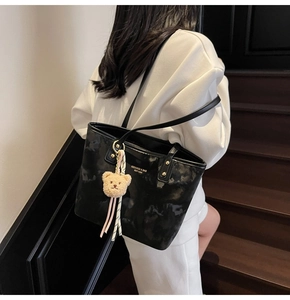 Detail view of black marble tote bag with golden rivets and cute teddy bear charm accessory