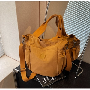 Detail of mustard yellow tote bag showing functional side pockets and woven handles