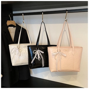 Detailed view of three embossed leather tote bags in white black and pink with lace charms