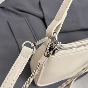 Detalle de los ganchos de metal plateado y la cadena en un bolso bandolera de cuero beige