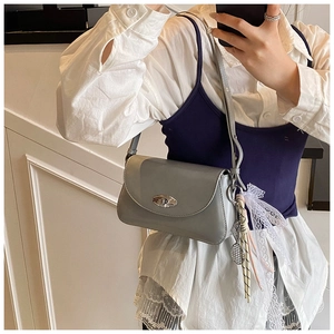 Gros plan du sac porté épaule en cuir verni gris avec fermoir argenté et ruban dentelle
