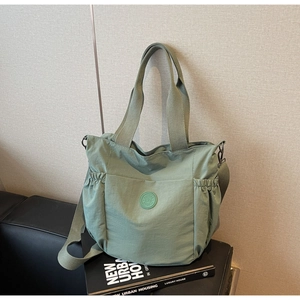 Detail of green nylon tote bag featuring drawstring side pockets and adjustable strap