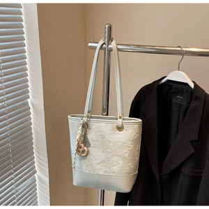Dettaglio borsa tote in pelle grigia goffrata con motivi floreali e finiture metalliche oro