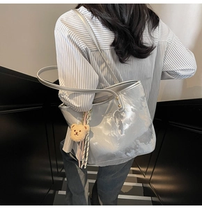 Detail of silver tote bag with cloud patterns and a plush bear charm on the strap