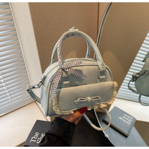 Detail van lichtblauwe tas met kanten rand, strik en handvat met lint omwikkeld