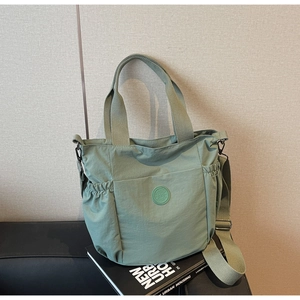 Detail of light green waterproof nylon tote bag with side elastic pockets and sturdy straps