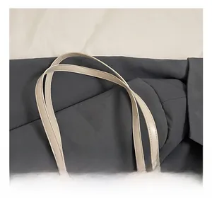 Detail of cream leather tote bag handles featuring elegant pearl and mesh charms