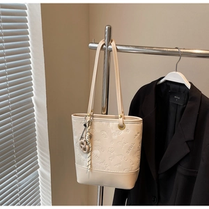 Dettaglio di motivi floreali a rilievo e farfalle su una borsa tote bianco crema