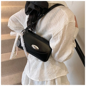 Détail du sac à bandoulière noir brillant avec ruban en dentelle et fermoir rotatif