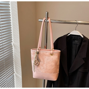 Dettaglio della borsa tote rosa in pelle PU goffrata con motivi floreali e ciondolo