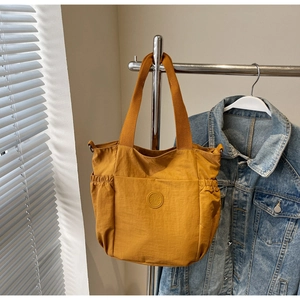 Detail of yellow canvas tote bag with fashion logo and side drawstring pockets