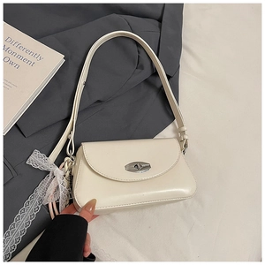 Détail du sac sous l'aisselle blanc crème avec fermoir rotatif argenté et nœud en dentelle