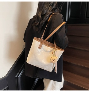 Chic cream tote bag with marble texture and brown handles shown on a model's shoulder