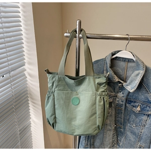 Detail view of large green canvas tote bag featuring side pockets and round logo