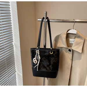 Dettaglio borsa tote nera goffrata floreale con ciondolo pretzel bianco su supporto metallo